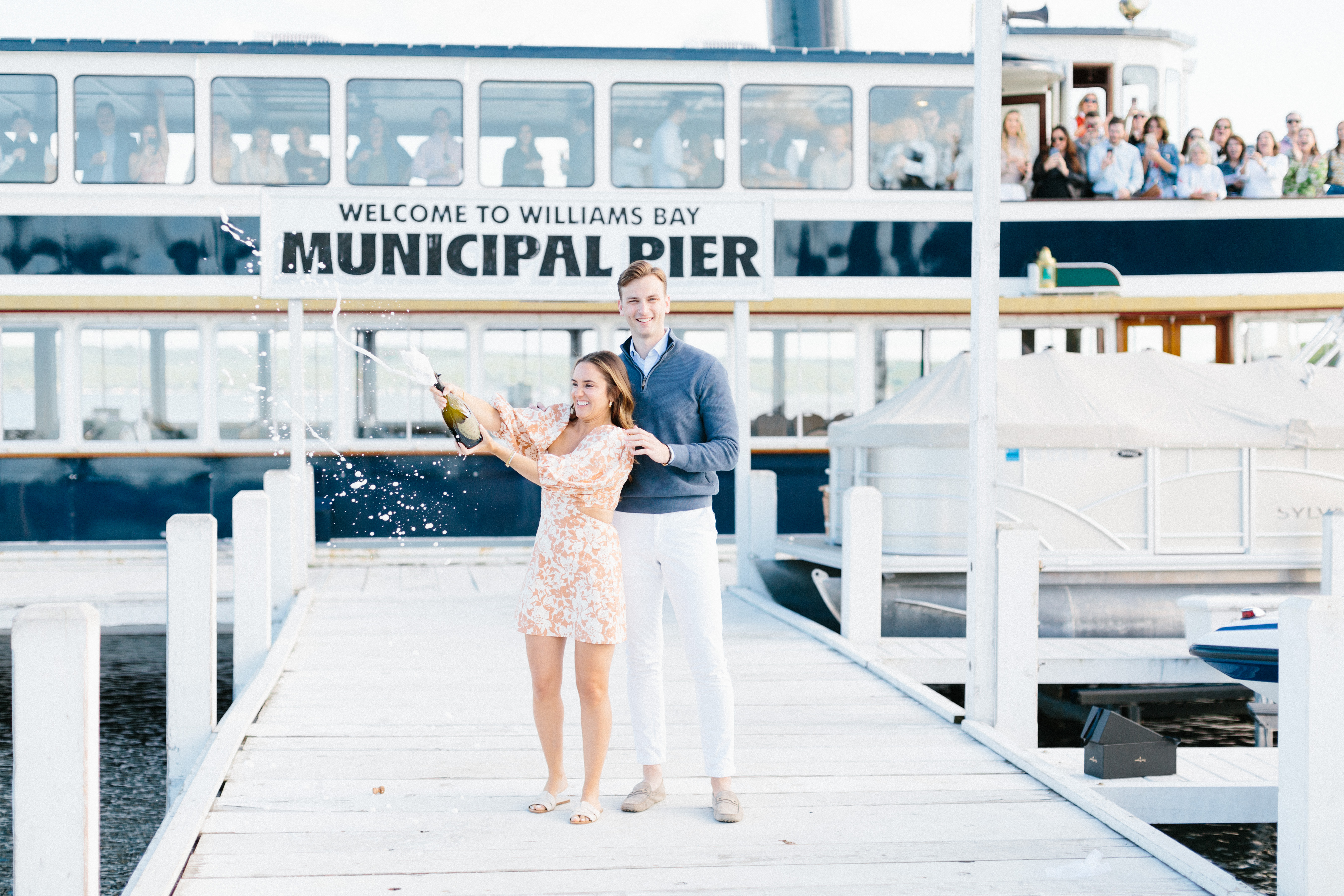Couple popping champagne bottle on pier